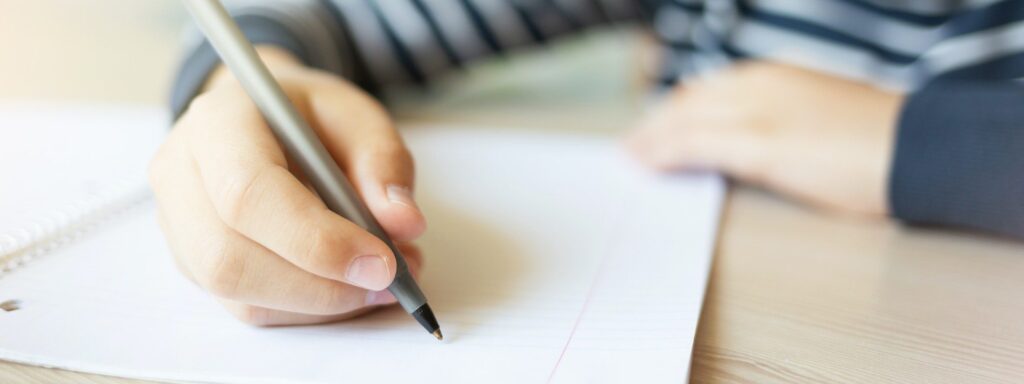 Adolescente escrevendo no caderno, praticando a redação. Prova do colégio Termomecânica. Processo seletivo Termomecânica.